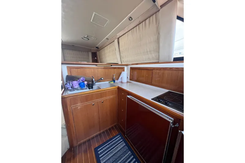 Slide: The Image of Interior of 2002 Riviera 54 Enclosed Flybridge yacht kitchen with wooden cabinetry and appliances. - 14