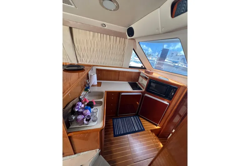 Slide: The Image of Interior of 2002 Riviera 54 Enclosed Flybridge yacht kitchen with wood finish and appliances. - 15