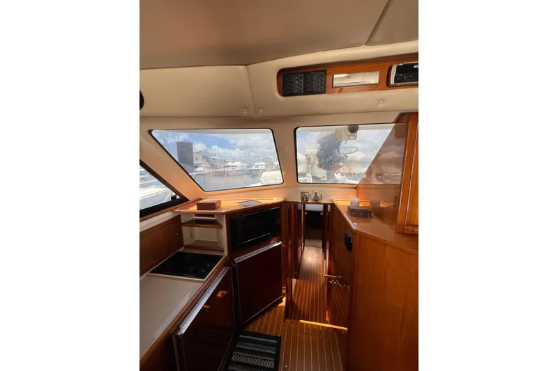 Slide: The Image of Interior of 2002 Riviera 54 Enclosed Flybridge yacht with wooden cabinetry and large windows. - 17
