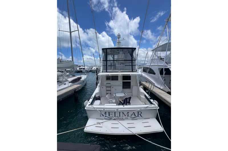 Slide: The Image of 2002 Riviera 54 Enclosed Flybridge yacht docked at marina under blue sky. - 2