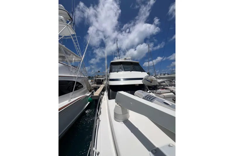 Slide: The Image of 2002 Riviera 54 Enclosed Flybridge yacht docked under a bright blue sky. - 7
