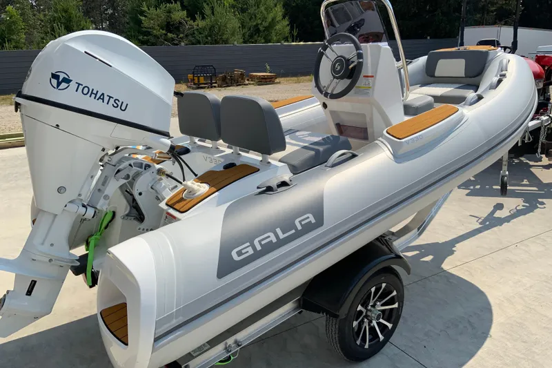 Slide: The Image of 2027 Gala V330 boat with Tohatsu engine on trailer, parked outdoors. - 11