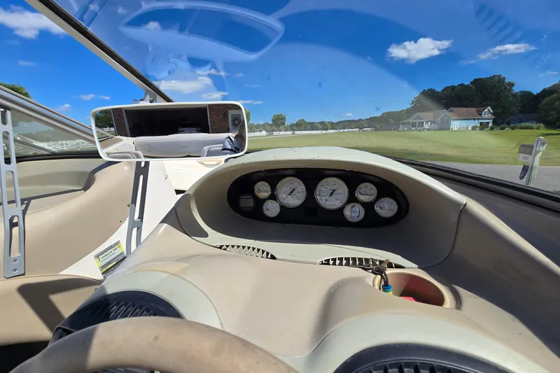 Slide: The Image of 1999 Bayliner 1850 Capri SS dashboard with gauges and rearview mirror, under clear blue sky. - 12