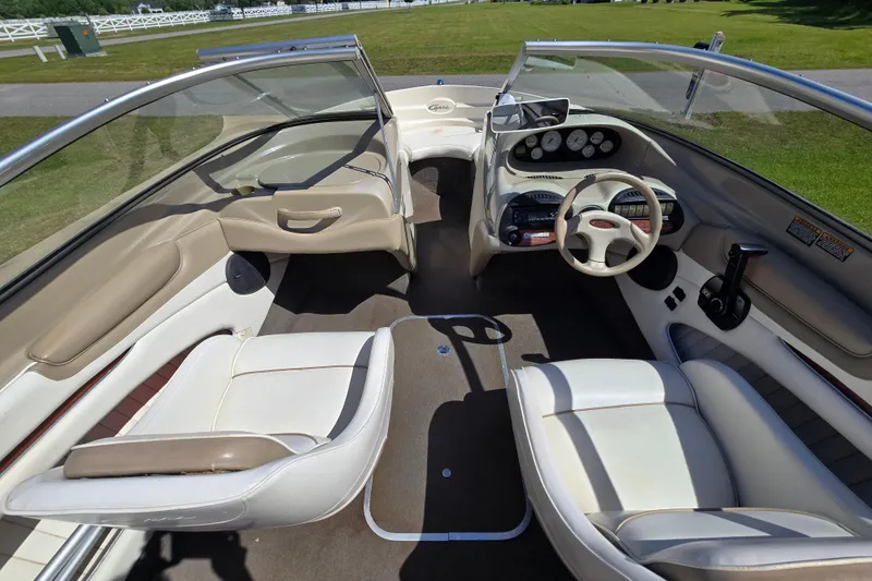 Slide: The Image of 1999 Bayliner 1850 Capri SS boat interior with beige seating and dashboard controls. - 14