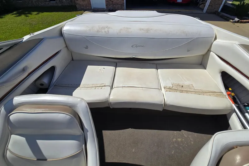 Slide: The Image of 1999 Bayliner 1850 Capri SS boat interior with worn white seating and storage compartments. - 25