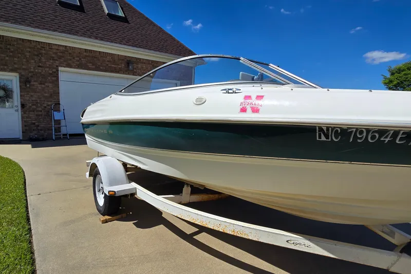 Slide: The Image of 1999 Bayliner 1850 Capri SS boat on trailer, parked in driveway under clear blue sky. - 28