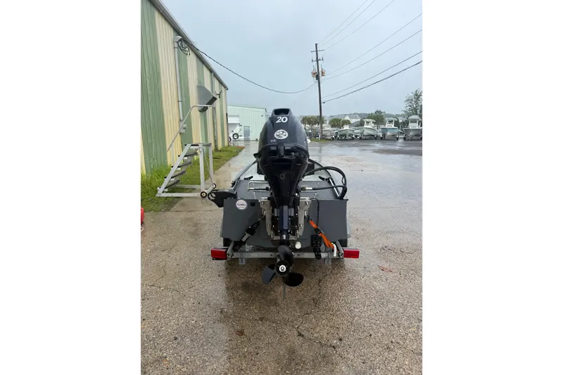 Slide: The Image of 2020 Gheenoe Lo Tide 25 boat with outboard motor, parked on wet pavement. - 2