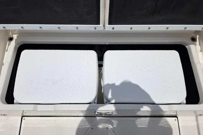 Slide: The Image of Open storage compartment on 2026 Solace 28HCS boat, featuring two white containers. - 18
