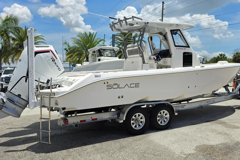 Slide: The Image of 2026 Solace 28HCS boat on trailer, featuring powerful outboard engine, parked outdoors. - 2