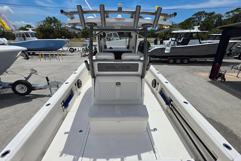 Slide: The Image of 2026 Solace 28HCS boat interior with seating and helm, parked in a marina. - 9