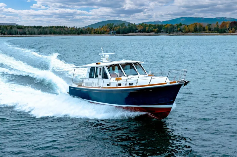 Slide: The Image of 2014 Grand Banks 46 Eastbay SX cruising on a scenic lake with forested hills. - 14
