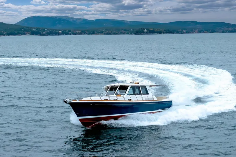 Slide: The Image of 2014 Grand Banks 46 Eastbay SX cruising on open water with scenic mountain backdrop. - 16