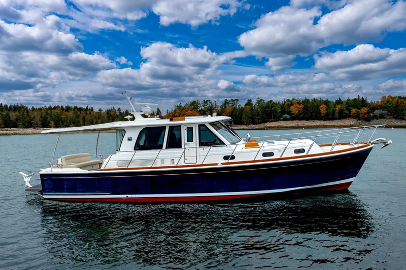 Slide: The Image of 2014 Grand Banks 46 Eastbay SX yacht on scenic water with cloudy sky backdrop. - 2