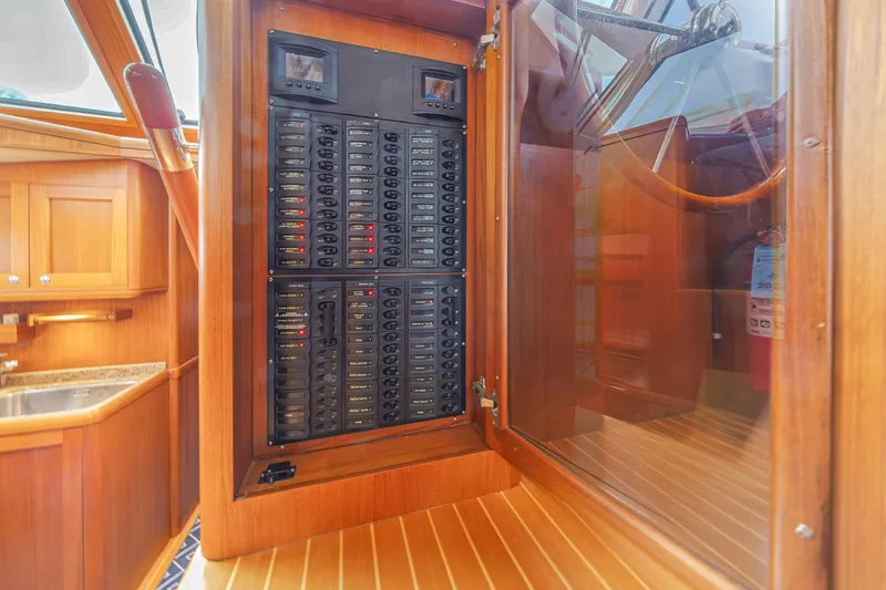 Slide: The Image of Electrical panel inside 2014 Grand Banks 46 Eastbay SX yacht, featuring wooden cabinetry and steering wheel. - 43