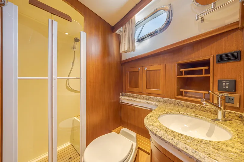 Slide: The Image of Luxurious 2014 Grand Banks 46 Eastbay SX yacht bathroom with shower, wooden cabinetry, and granite countertop. - 63