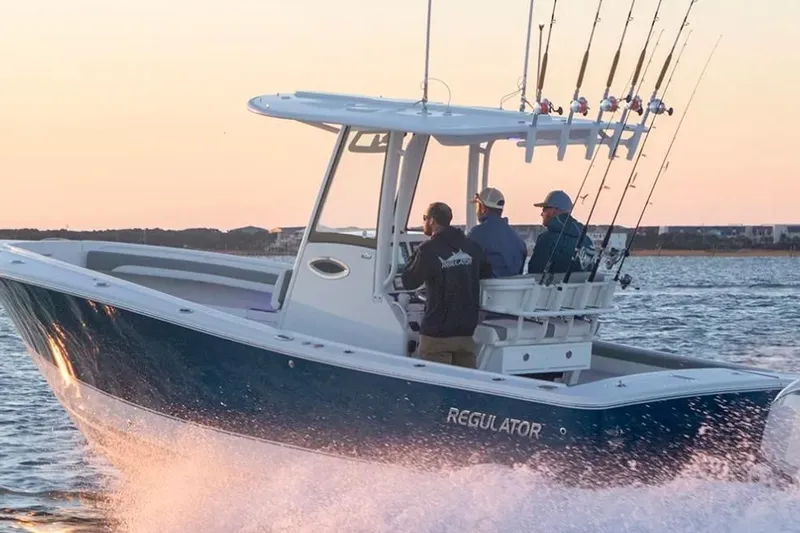 The Image of 2027 Regulator 25 on the water at sunset, featuring fishing rods and three people on board. - 0