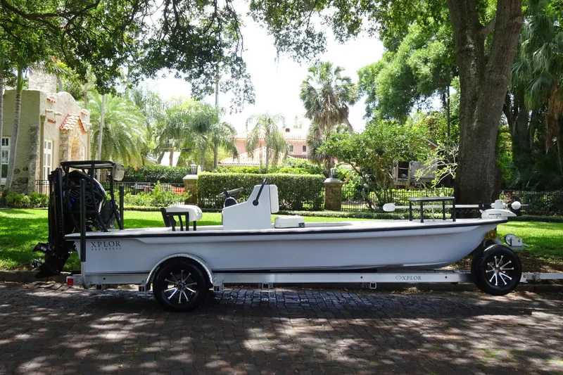 Slide: The Image of 2024 Xplor X18 Delta D18 boat on trailer, parked in a lush, residential area. - 4