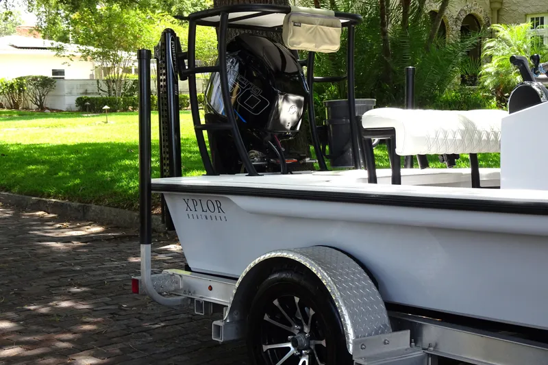 Slide: The Image of 2024 Xplor X18 Delta D18 boat on trailer, parked in a sunny residential area. - 9