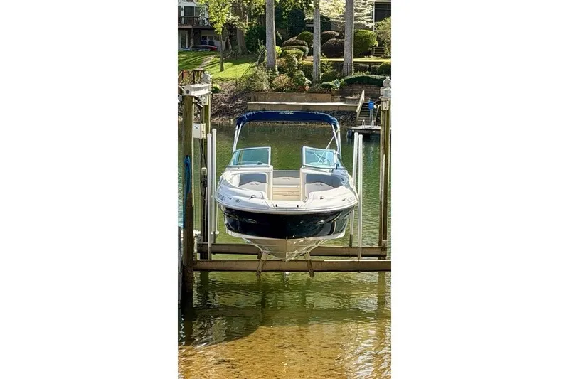Slide: The Image of 2008 Sea Ray 240 Sundeck boat on lift, docked by lush greenery. - 4