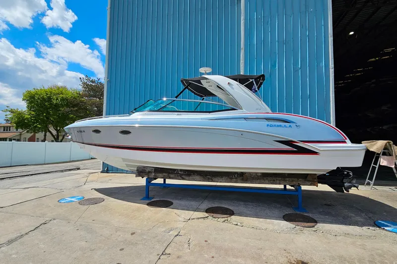 Slide: The Image of 2013 Formula 310 FX5 boat on display outside a blue warehouse under a sunny sky. - 2
