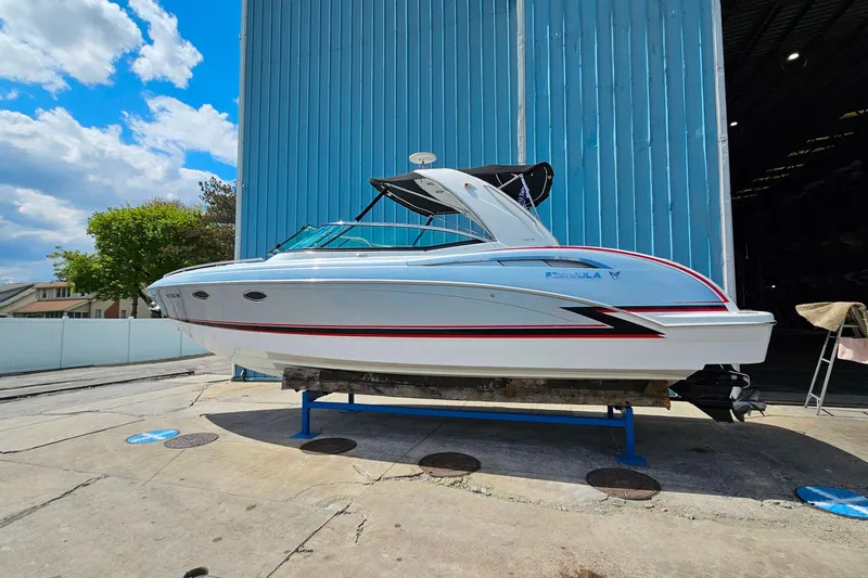 Slide: The Image of 2013 Formula 310 FX5 boat on display outside a blue warehouse under a sunny sky. - 32