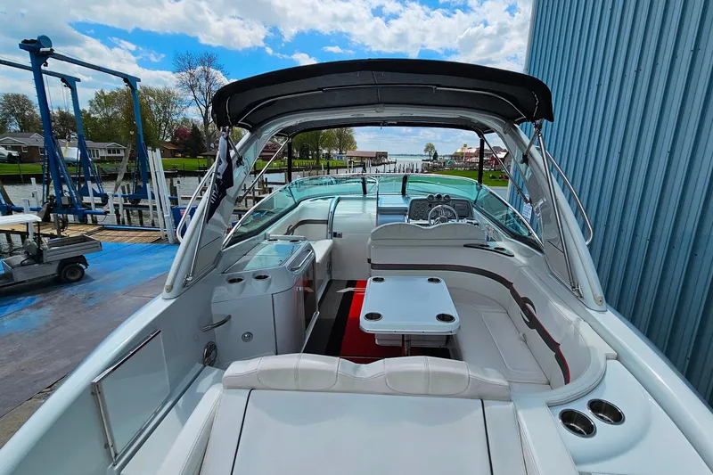 Slide: The Image of 2013 Formula 310 FX5 boat interior with seating and table, docked by a marina. - 8