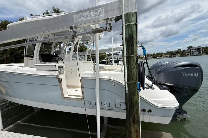 Slide: The Image of 2022 Robalo R302 Center Console boat docked with Yamaha engines, under cloudy sky. - 2