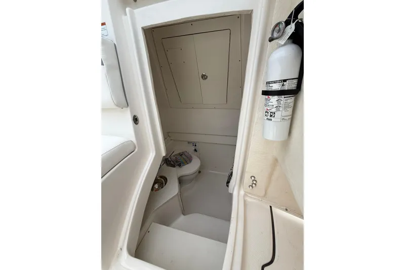 Slide: The Image of 2022 Robalo R302 Center Console boat interior with toilet and fire extinguisher. - 6