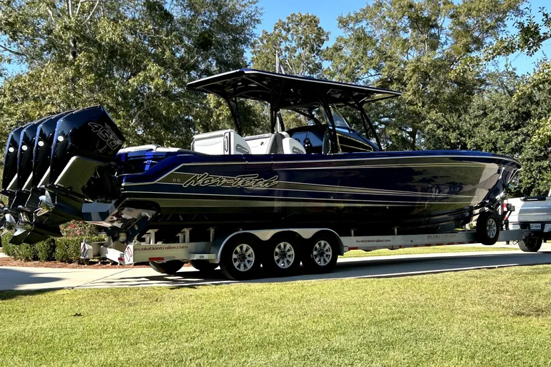 Slide: The Image of 2021 Nortech 390 Sport boat on trailer, featuring four powerful engines, parked outdoors. - 4
