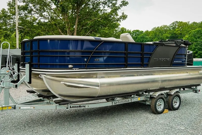 Slide: The Image of 2026 Trifecta LE 22RF pontoon boat on trailer, parked outdoors. - 2