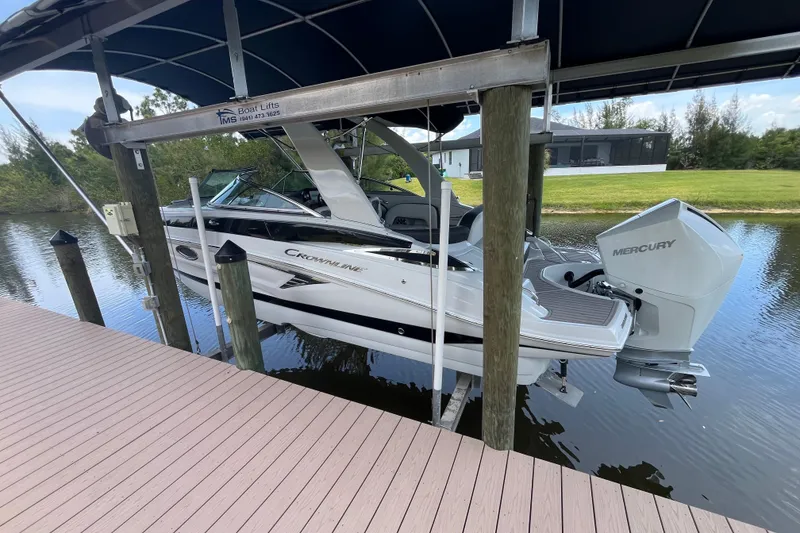 The Image of 2022 Crownline 260 XSS boat on lift, docked by a serene waterway. - 0