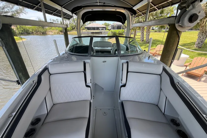 Slide: The Image of 2022 Crownline 260 XSS boat interior with luxurious seating, docked by a scenic lake. - 12