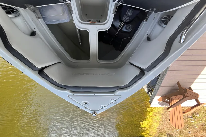 Slide: The Image of 2022 Crownline 260 XSS boat interior with seating and storage, docked by a wooden deck. - 18