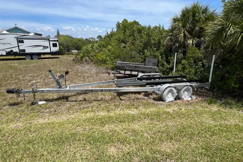 Slide: The Image of Trailer for 2022 Crownline 260 XSS boat parked on grassy area near trees. - 31