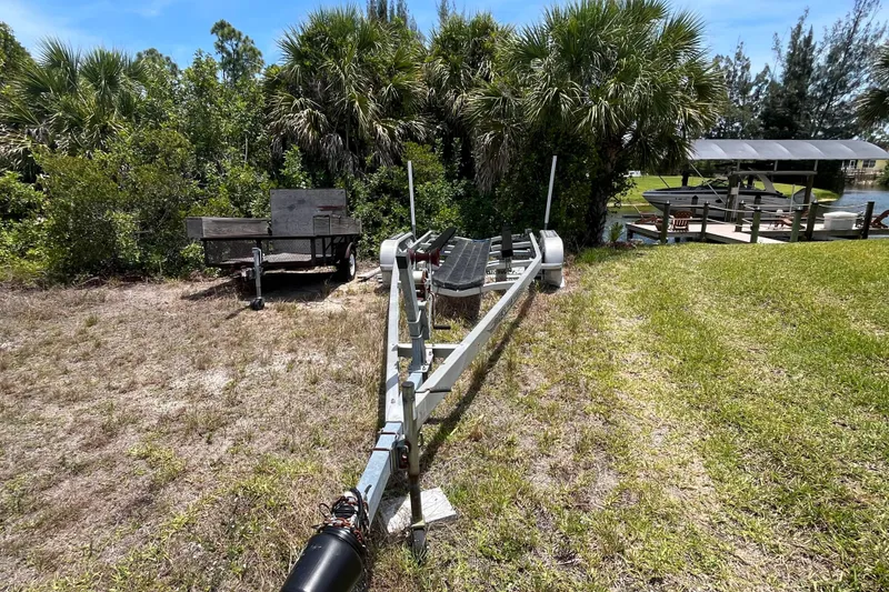 Slide: The Image of Boat trailer on grassy area near docked boats, surrounded by lush greenery. - 32
