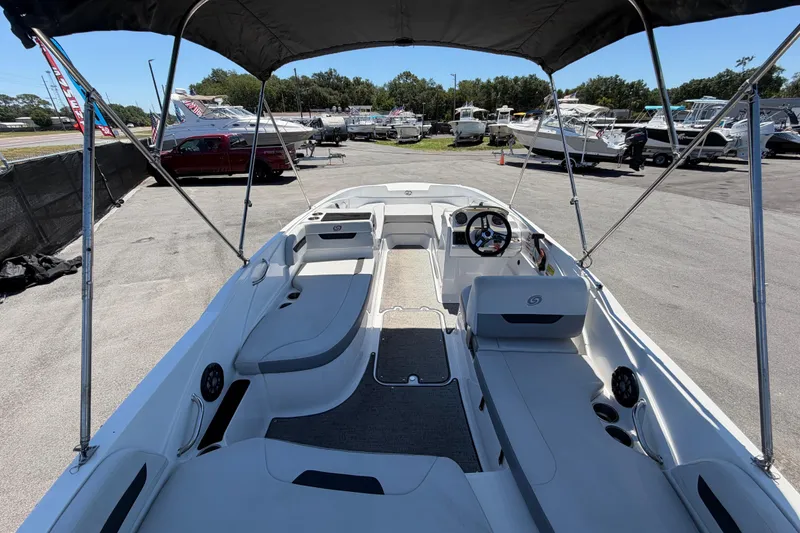 Slide: The Image of 2022 Hurricane SunDeck Sport 185 OB boat interior with canopy, parked in a marina. - 11