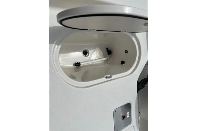 Slide: The Image of 2026 Carolina Skiff 21 LS boat compartment with open lid and visible fittings. - 27