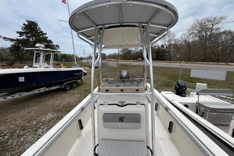 Slide: The Image of 2026 Carolina Skiff 21 LS boat with T-top, parked outdoors near other boats. - 7