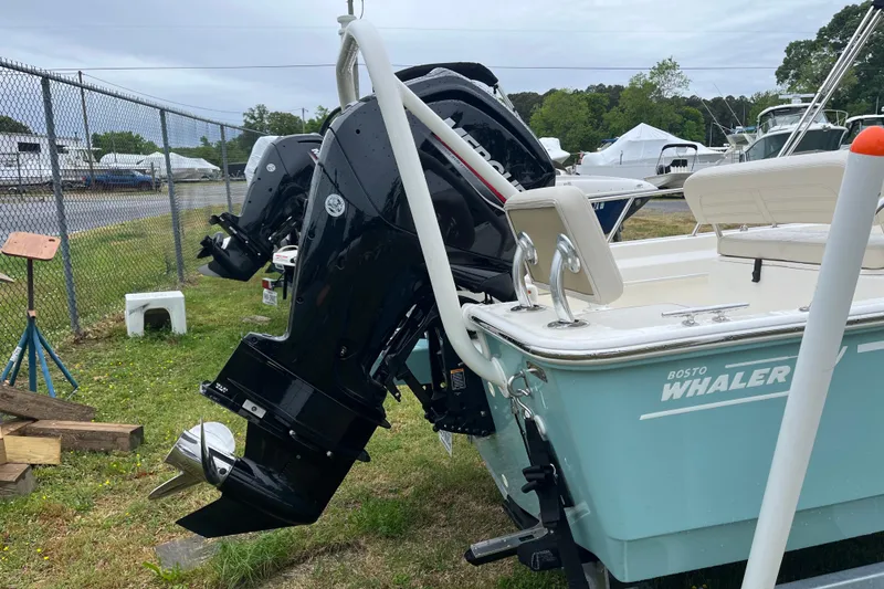 Slide: The Image of 2023 Boston Whaler 170 Montauk boat with dual outboard motors in a storage yard. - 14
