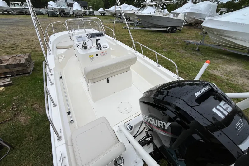 Slide: The Image of 2023 Boston Whaler 170 Montauk boat with Mercury 115 engine, parked on grass. - 6