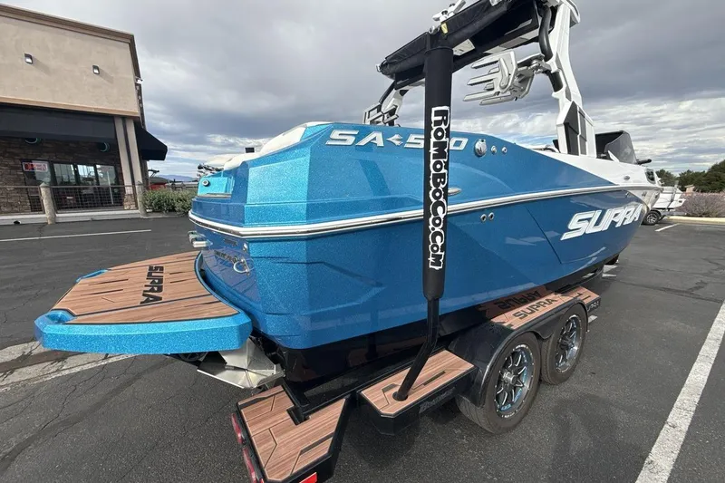 Slide: The Image of 2024 Supra SA 550 boat in vibrant blue on a trailer, parked outdoors. - 5