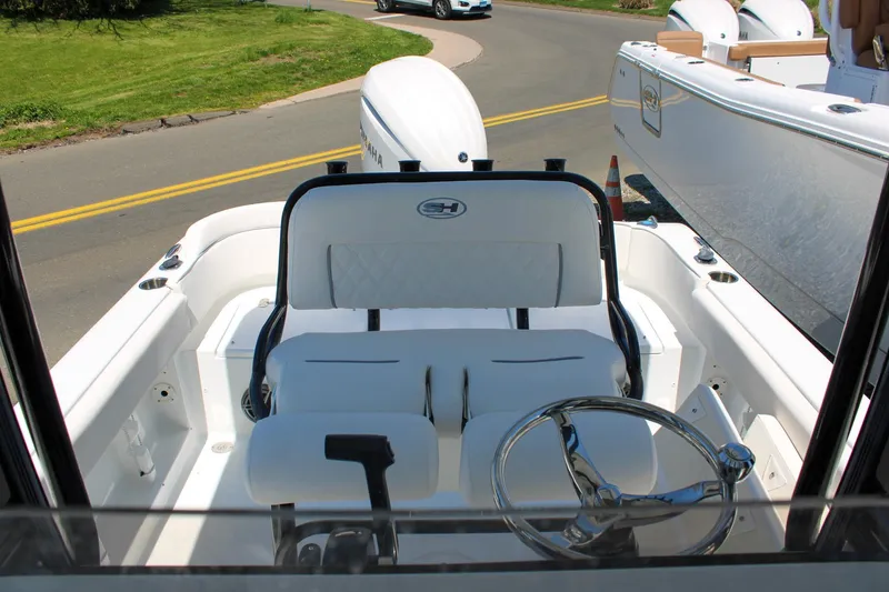 Slide: The Image of 2026 Sea Hunt Ultra 219 boat interior with steering wheel and seating, parked on a road. - 20