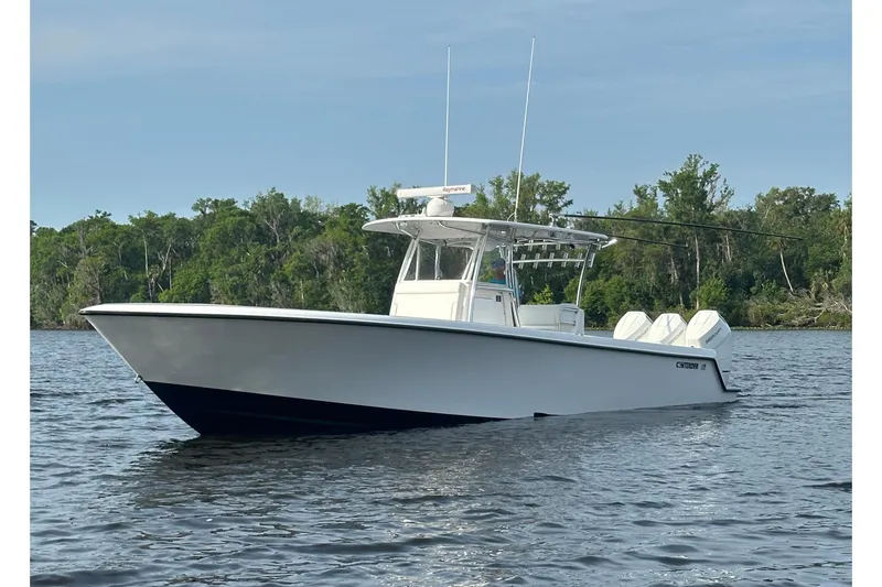 Slide: The Image of 2024 Contender 39 ST boat on calm water with forest backdrop. - 2
