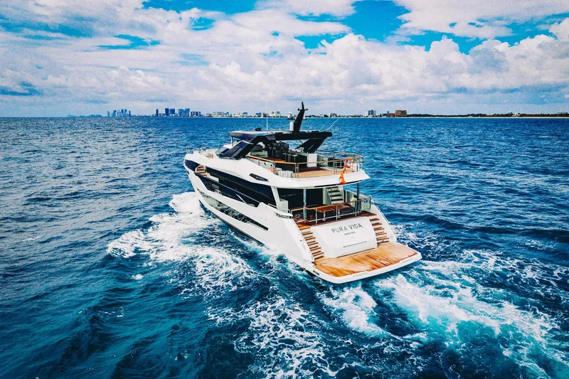 Slide: The Image of 2024 Sunseeker 100 Yacht cruising on open sea with city skyline in background. - 6