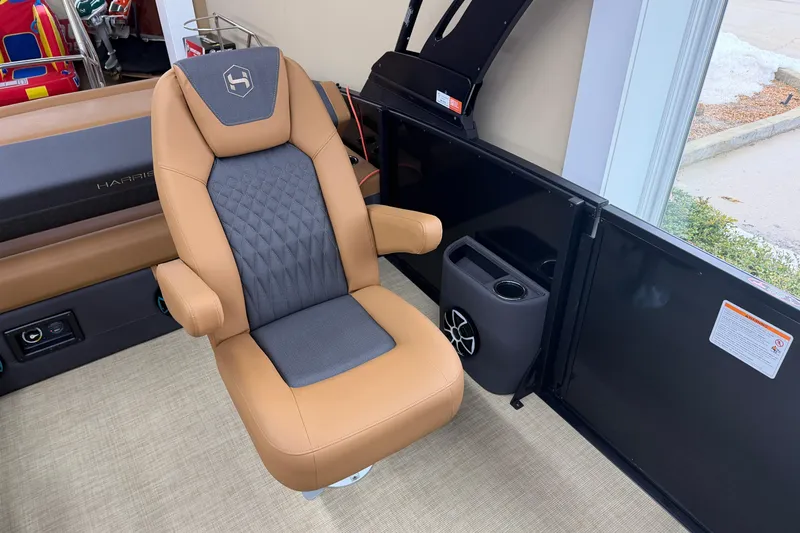 Slide: The Image of 2026 Harris Sunliner 230 boat seat with tan and gray upholstery, cup holder, and speaker. - 8