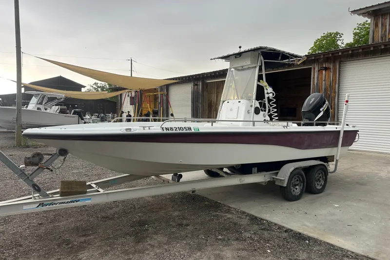 The Image of 2002 Polar 2300 Bay boat on trailer, parked outdoors near wooden buildings. - 0