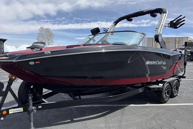 The Image of 2023 MasterCraft NXT22 boat with sleek black and red design on a trailer. - 1