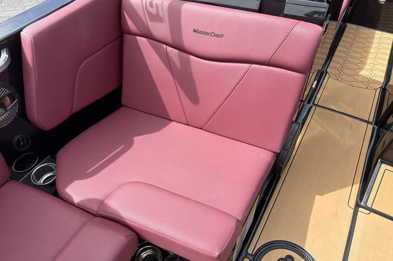Slide: The Image of 2023 MasterCraft NXT22 boat interior with pink seating and wood flooring. - 17