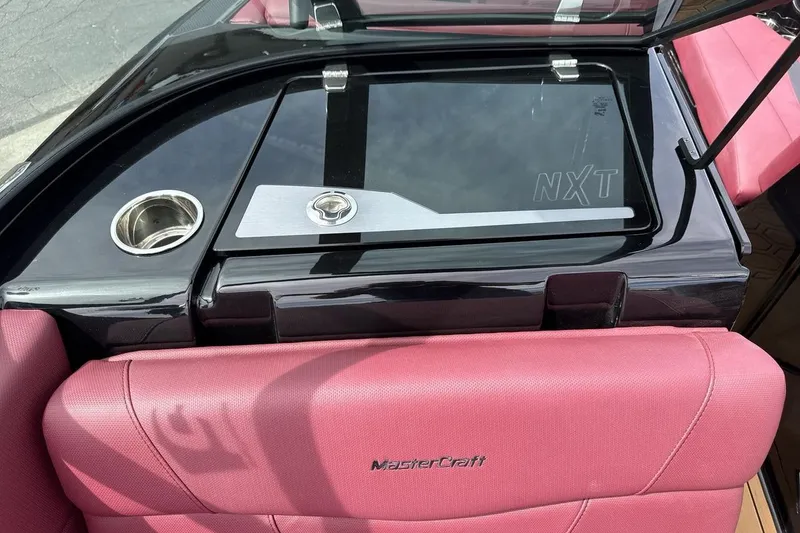 Slide: The Image of 2023 MasterCraft NXT22 boat interior with pink seating and sleek black dashboard. - 18