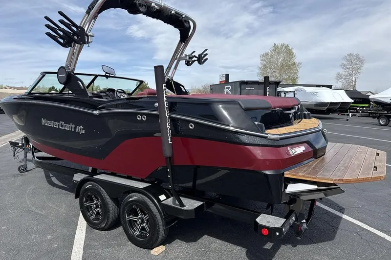 Slide: The Image of 2023 MasterCraft NXT22 boat on trailer, featuring sleek black and red design. - 3